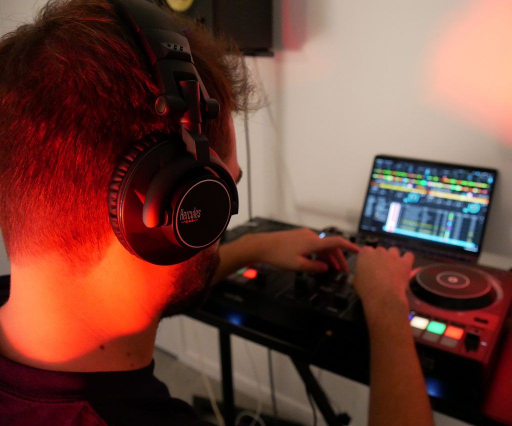 DJ wearing over-ear headphones while mixing music on professional DJ controller setup